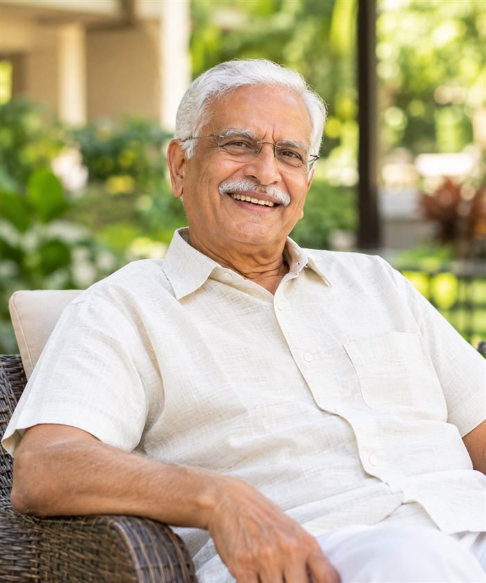 Portrait of Mr. Krishnan, a SilverNest member, smiling in the garden